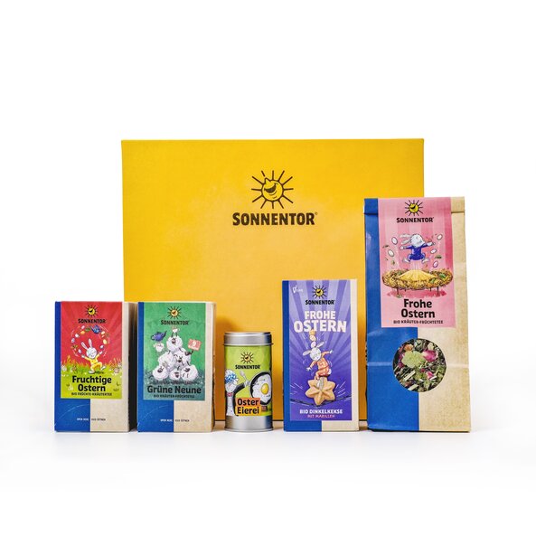 Foto mit den im Geschenkkarton enthaltenen Produkten, Grüne Neune Tee, Frohe Ostern Tee, Fruchtige Ostern Tee, Frohe Ostern Kekse und Oster Eierei Gewürzmischung.