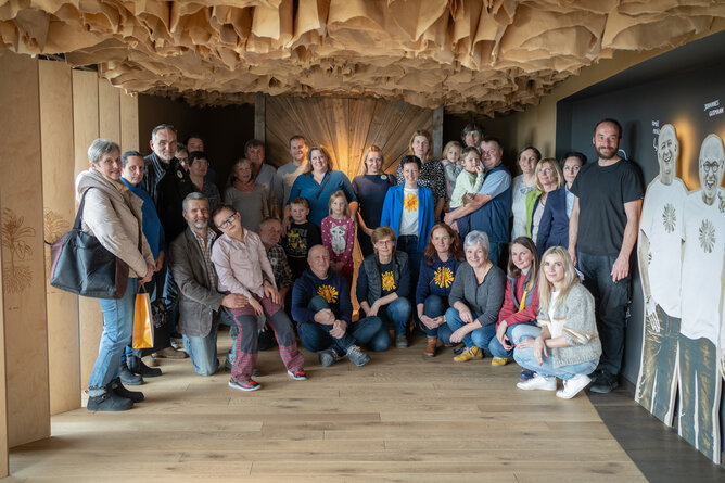 Na fotografii pózuje před sluneční branou na exkurzní trase skupina přibližně třiceti lidí včetně několika dětí. Jedná se o pěstitele, jejich rodiny a některé spolupracovníky SONNENTORU. | © SONNENTOR